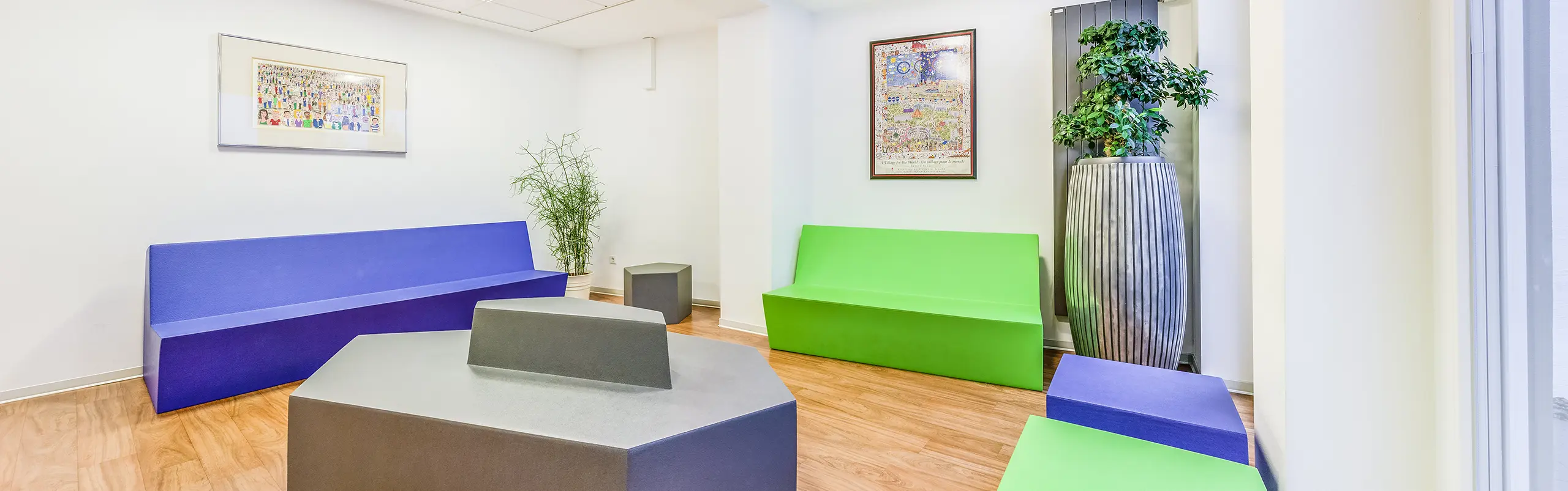 Moderne Zahnarztpraxis mit Behandlungsstuhl, zwei geometrischen Hockern und einem Kunstbild an der Wand