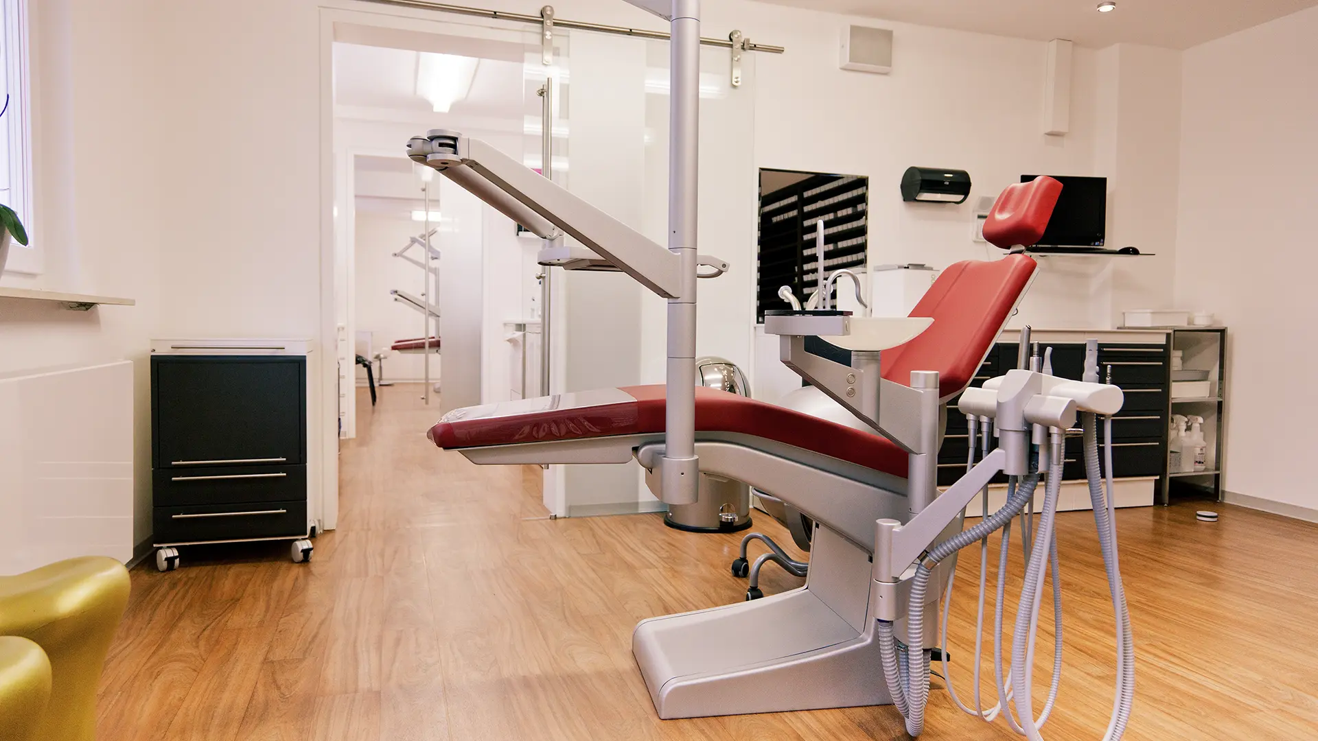 Zahnarztpraxis mit roten Behandlungsstühlen, zahnärztlichen Geräten und weißen Wänden